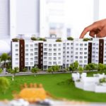 İnşaat aşamasındaki konut projesi maketi ve kat planı incelemesi.