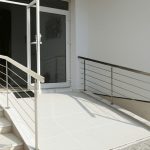 Geniş kapıları ve tekerlekli sandalye rampası bulunan erişilebilir konut mimarisi ve bina girişi tasarımı.